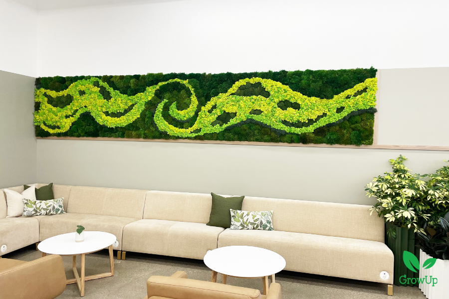 Modern office lounge area by GrowUp featuring a long, custom preserved moss wall installation designed with vibrant green swirling patterns that mimic natural curves above a beige sectional sofa.