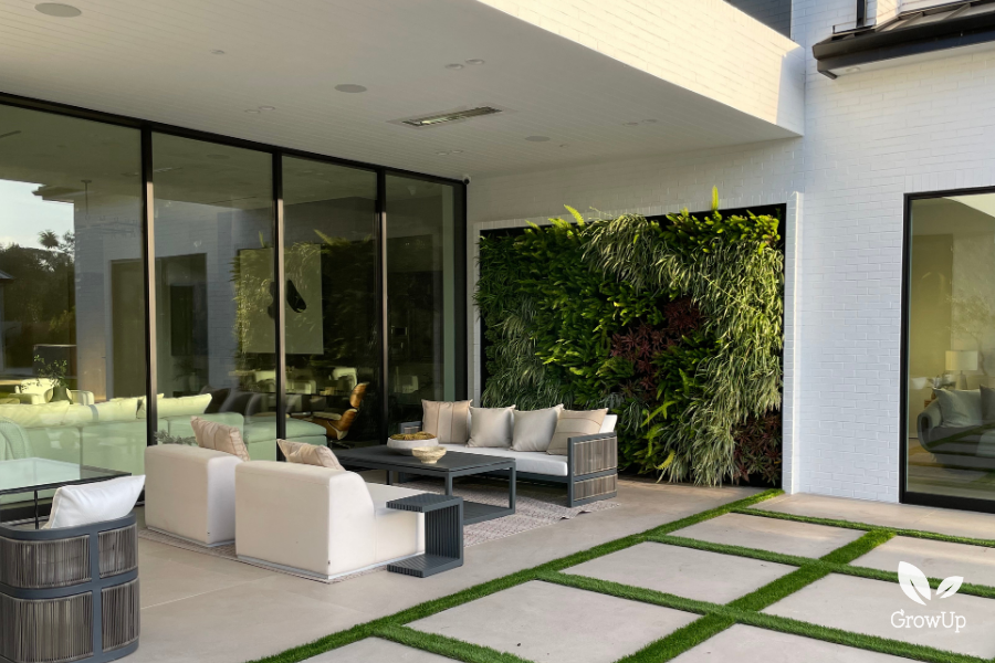 A modern luxury patio lounge area with white outdoor sofas situated in front of an embedded vertical living wall system.