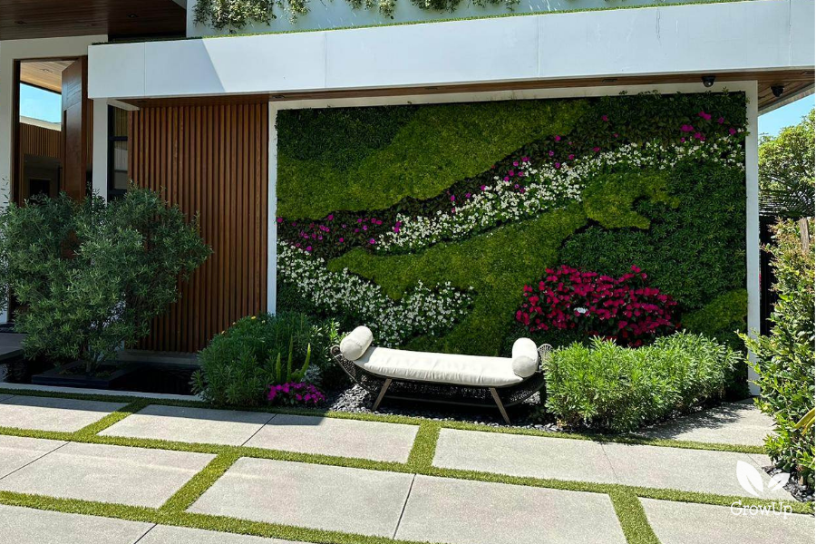 outdoor greenwall with flowers and a white bench infront of it