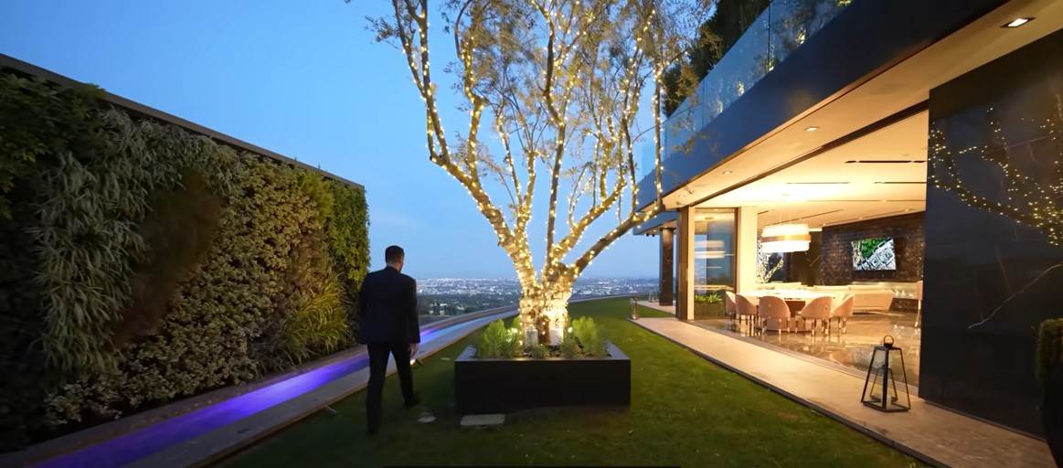 Living wall running along the lawn of the Bel Air residence at night, beside a lit tree and the glass-fronted house