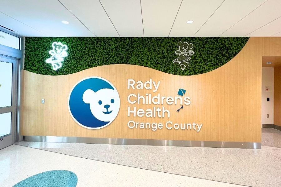 Rady Children’s Health Orange County lobby featuring a moss wall with LED bear outlines and curved wood panel design.