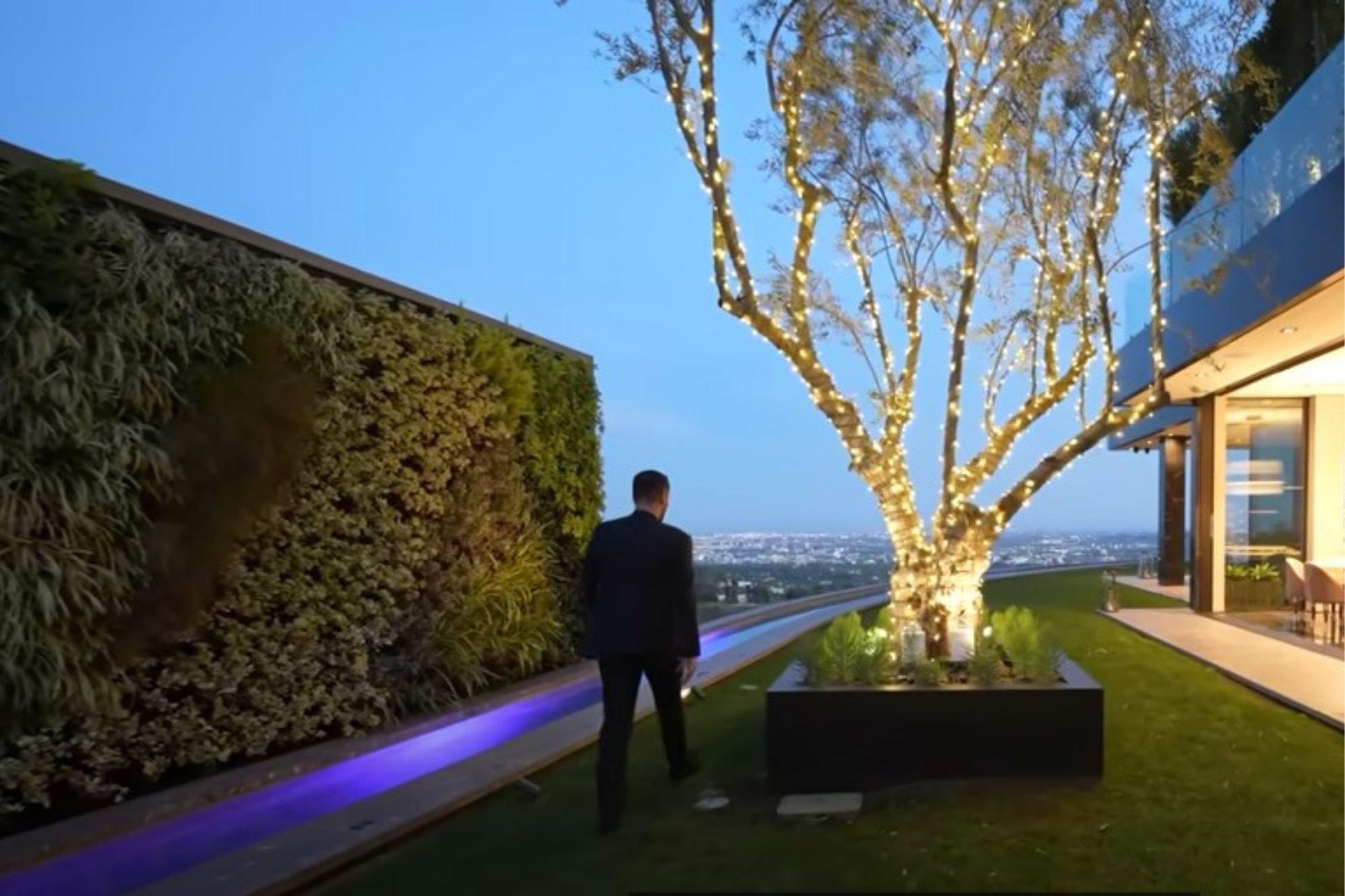 Living wall running along the lawn of the Bel Air residence at night, beside a lit tree and the glass-fronted house