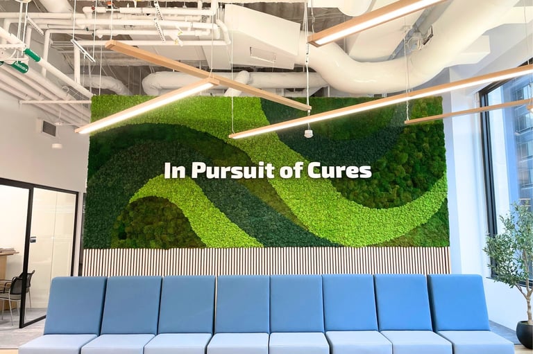 Lobby moss feature wall in four shades of green above wooden slats, with a row of blue seating