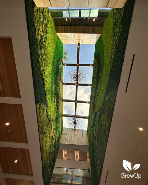 A massive, custom-designed dual green moss wall featuring sweeping organic waves stretching across the high ceiling.