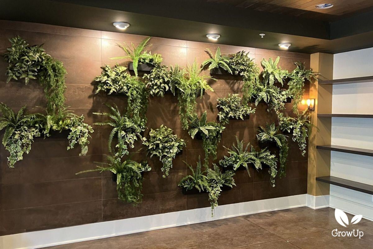Front view of faux ferns and foliage in wall-mounted trays, with the tiled wall visible between them