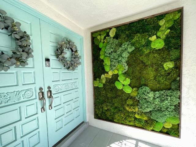 Large moss wall next to blue doors in an outdoor entry way