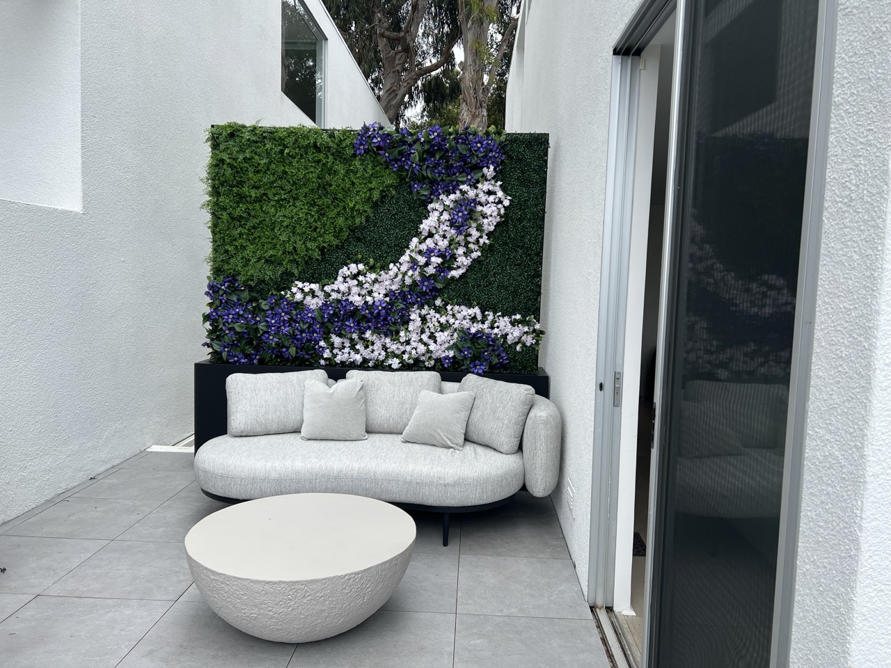 Patterned faux greenwall with purple flowers in a residential patio area
