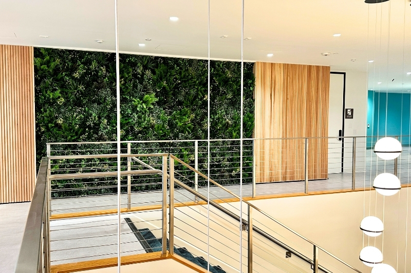 Faux greenwall in a hallway next to a staircase in a residence. 