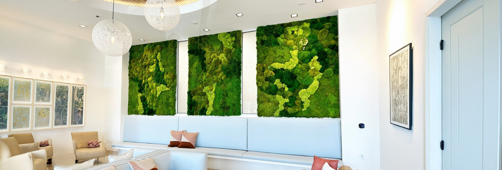 Three lush moss walls on a wall in a waiting room seating area.