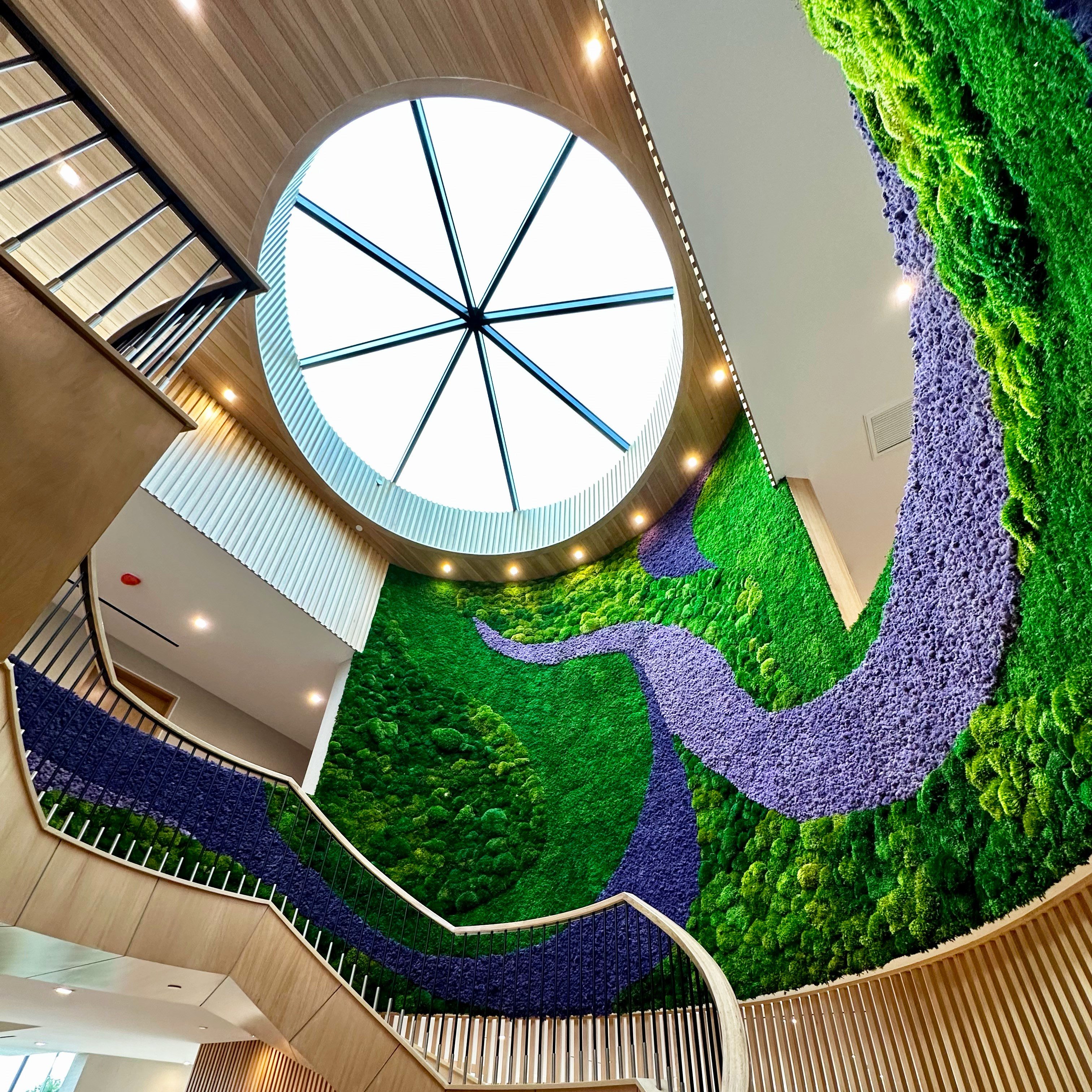 Vibrant moss wall with purple accent moss curved around a residential staircase.