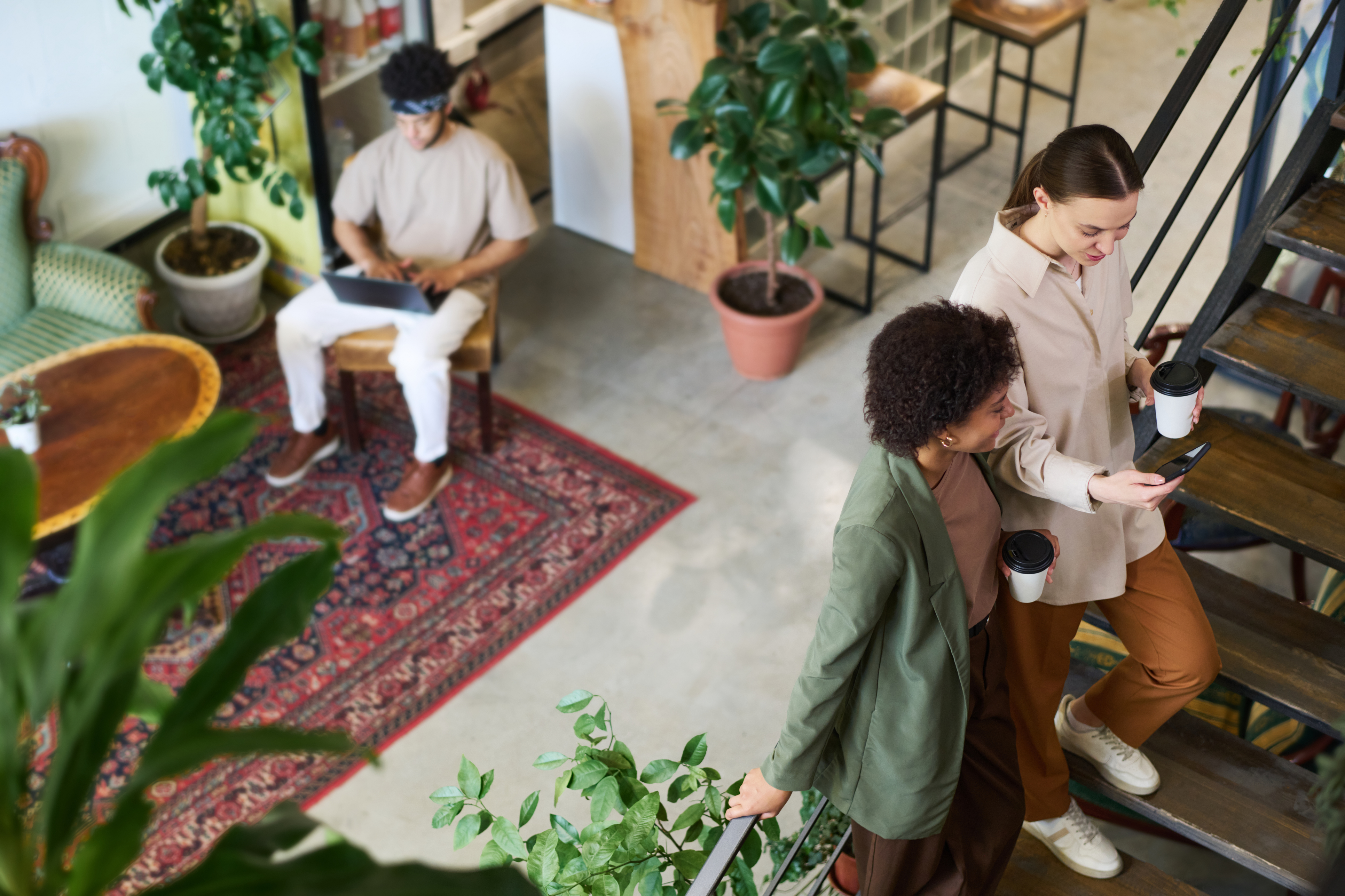 Modern workplace with plants and colorful decor and people chatting.